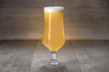 A delicious New England IPA beer in a craft brewery tulip glass, on wooden background