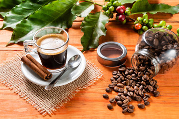 Glass of clear glass of hot coffee on wooden table. Orange wood pinus.