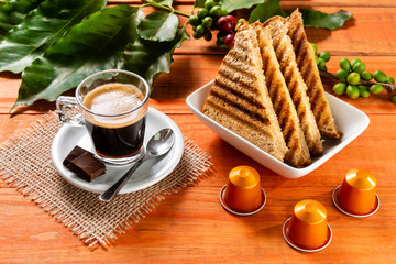 Glass of clear glass of hot coffee on wooden table. Orange wood pinus.