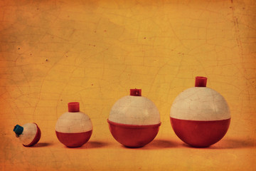 Old vintage fishing bobbers in a row on a yellow background