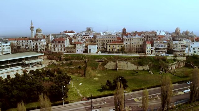 Lift aerial shot of Old Town Constanta, Romania, revealing the Roman Edifice with mosaique and the architecture of the ancient city Tomis