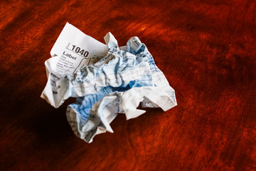Paper tax form, old school style, crumpled up on a wooden table