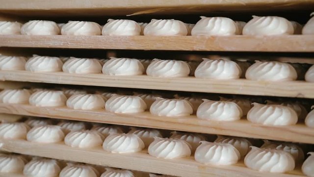 Panorama of many sweets white marshmallows stored in wooden racks in the warehouse of the confectionery factory. The concept of ready-made sweet products