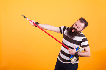Funny bearded rockstar playing virtual guitar with broom