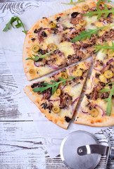 Pizza with fish, cheese and arugula on white wooden table