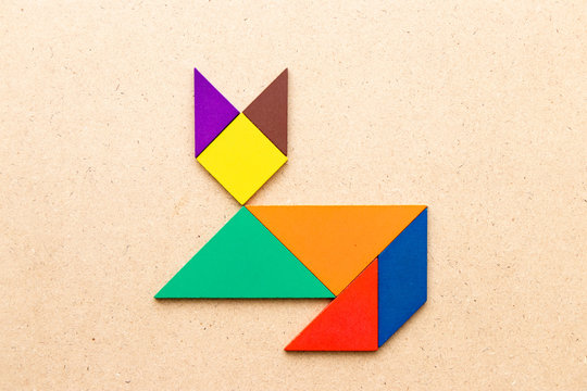 Color tangram puzzle in cat shape on wood background