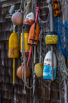 Bright and colorful lobster floats and lobster buoys hanging on wood shingled wall