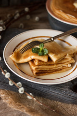 Homemade thin crepes with honey, pancakes on wooden rustic background