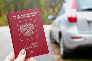 Russian passport in the hand of woman and car background