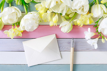 Beautiful white tulips and yellow freesias on striped wooden background