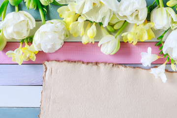 Beautiful white tulips and yellow freesias on striped wooden background