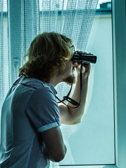 Man with binoculars spying on neighbors