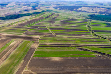 Aerial drone view of agricultural fields of plowed crops