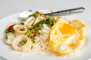Close up of rice topped with stir-fried pork squid and basil.