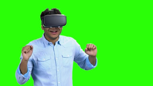 Portrait of young scared man using virtual reality glasses. Green Chroma Key background. Future technology and innovation concept.