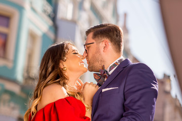Beautiful couple posing outdoor, happy woman in red dress and handsome man posing in blue suit