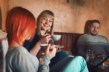 Smoke hookah shisha in bar and nightclub, team of friends two girls and man, have fun, drink tea.