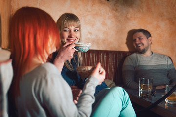 Smoke hookah shisha in bar and nightclub, team of friends two girls and man, have fun, drink tea.