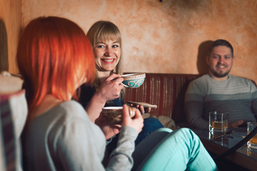 Smoke hookah shisha in bar and nightclub, team of friends two girls and man, have fun, drink tea.