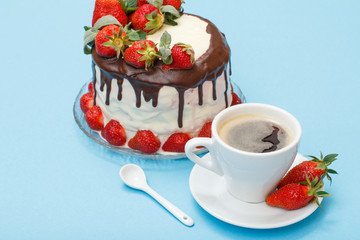 Homemade chocolate cake decorated with fresh strawberries on glass plate and cup of coffee with saucer.