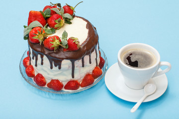 Homemade chocolate cake decorated with fresh strawberries on glass plate and cup of coffee with saucer.