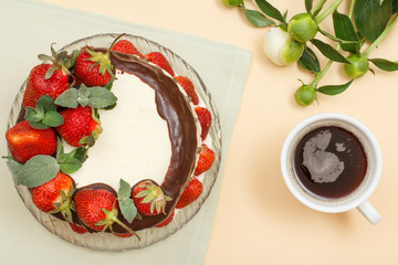 Homemade chocolate cake decorated with fresh strawberries on glass plate and bouquet of peonies.