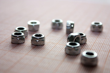 Steel gray nuts lying randomly against the background of red graph paper