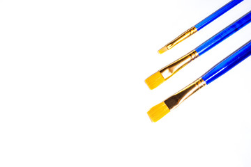 Three blue synthetic art brushes on a white background