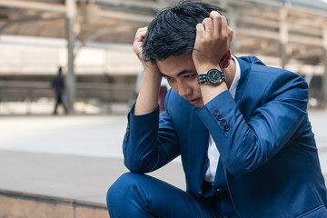 Sad yound and handsome businessman sit on the stair and have bad feeling.