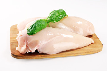 Raw chicken breasts and spices on wooden cutting board, close up