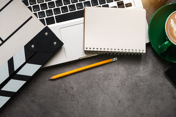 office stuff with Movie clapper, laptop, smartphone, tablet, coffee cup, pen, notepad and documents...