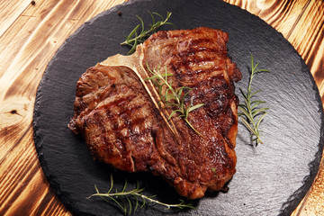 Grilled T-bone steak on stone cutting board.