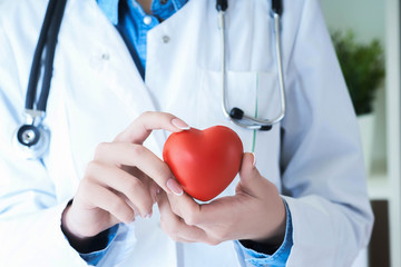 Female medicine doctor hold in hands red toy heart close -up. Cardio therapeutic student education...