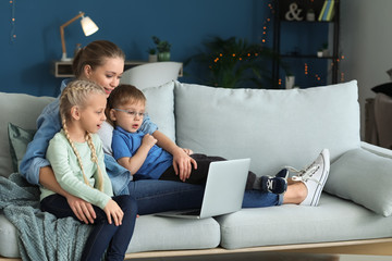 Young mother with little children watching cartoons at home