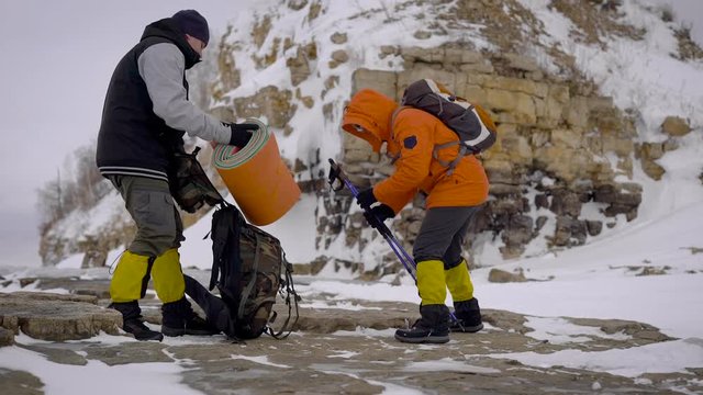 Two Friends Repacking Trekking Equipment After Rest