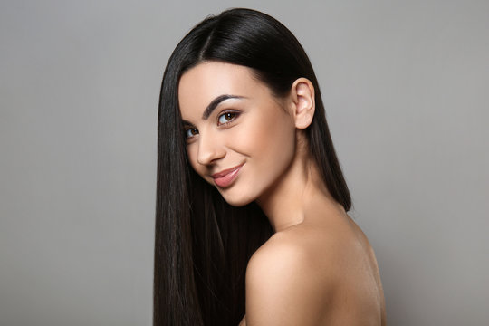 Portrait Of Beautiful Young Woman With Healthy Long Hair On Grey Background