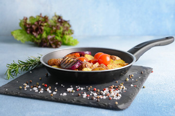 Frying pan with tasty baked potato on table