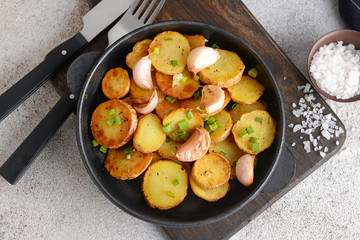 Frying pan with tasty baked potato on table