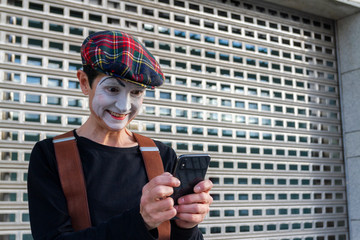 mime looks at the mobile phone with a happy face