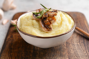 Bowl with tasty mashed potato on wooden board