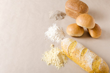 Different types of dread and piles of flour on brown craft paper.Empty space for your design