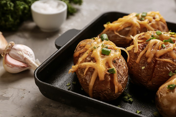 Frying pan with tasty baked potato on table
