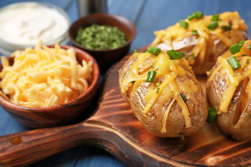 Tasty baked potato on wooden board