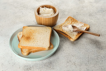 Tasty toasted bread with coconut oil on light background