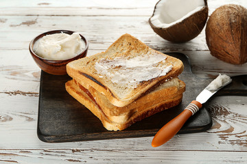 Tasty toasted bread with coconut oil on wooden background