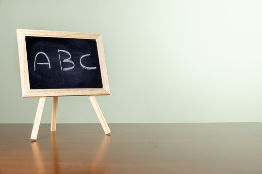 Blackboard with easel stand on wooden table. Written "A B C" on the blackboard With copy space. education concept.