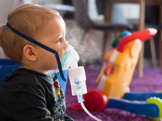 Blonde caucasian small boy with oxygen mask at home