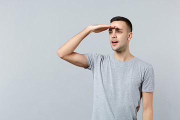 Attractive young man in casual clothes holding hand at forehead looking far away�distance...