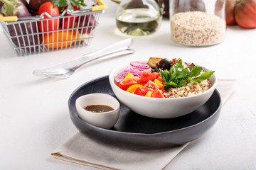 Quinoa salad with roasted eggplant, fresh tomatoes and red onion.   Vegan or vegetarian food. Healthy salad in bowl served on white table.