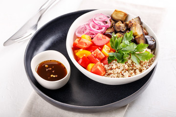 Quinoa salad with roasted eggplant, fresh tomatoes and red onion.   Vegan or vegetarian food. Healthy salad in bowl served on white table.